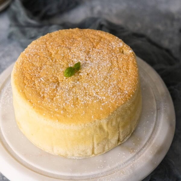 Yogurt cake on a marble cake stand with a piece of hunter green cloth under it.