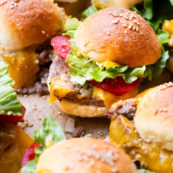 Mini cheeseburger sliders with lettuce and tomato slices.