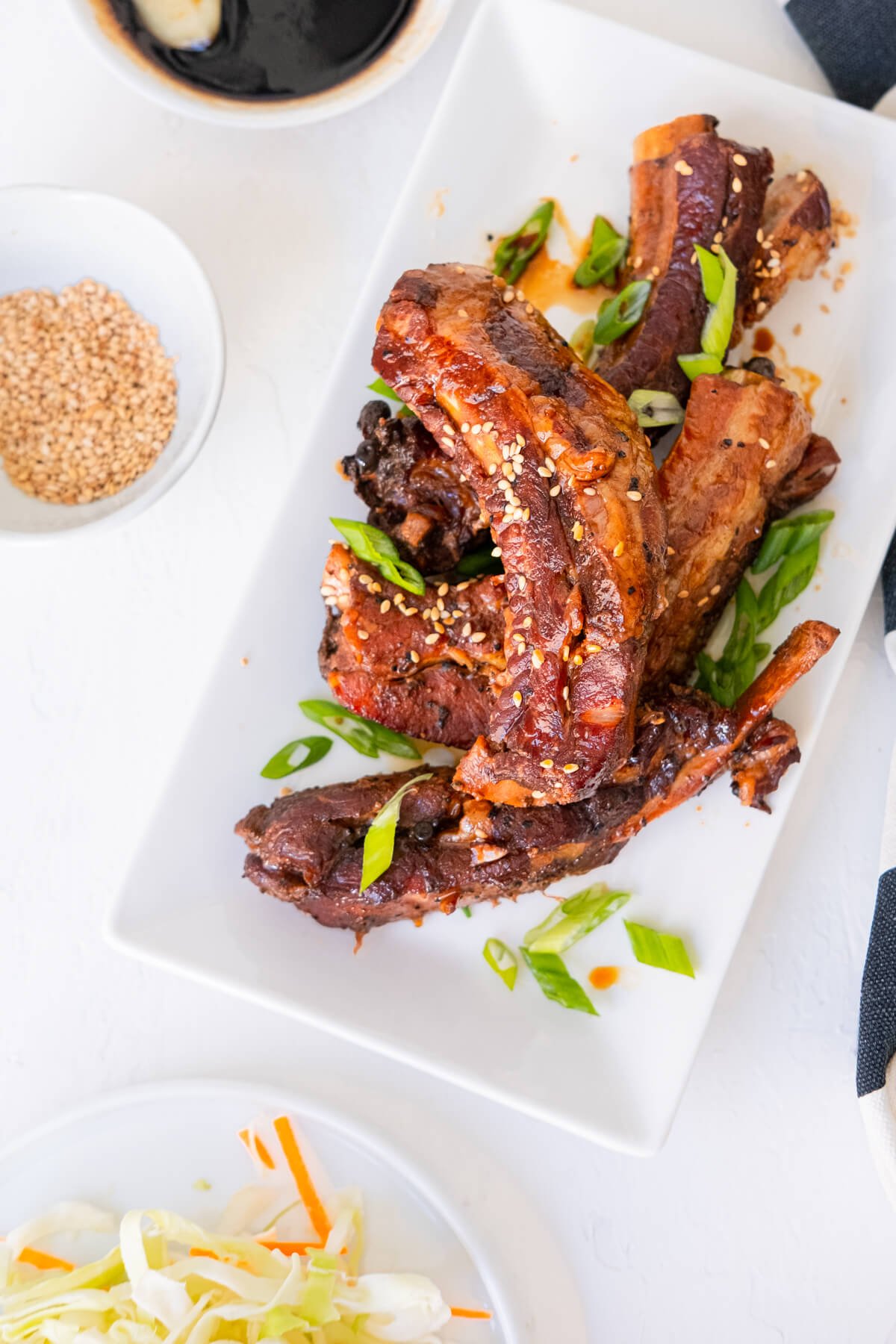 Slow cooker teriyaki ribs served with white sesame seeds, sauce and slaw. 