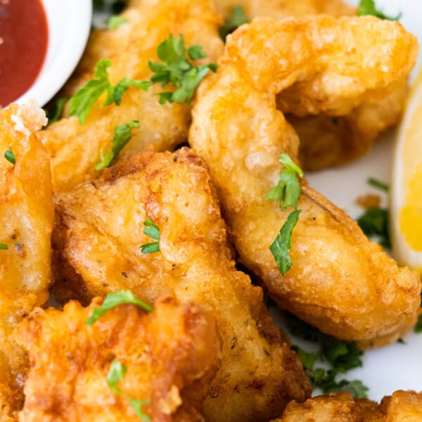 Beer-battered fish with freshly chopped parsley on top and served with ketchup aside.