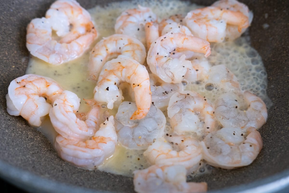 Shrimps simmered in butter and minced garlic in the pan.