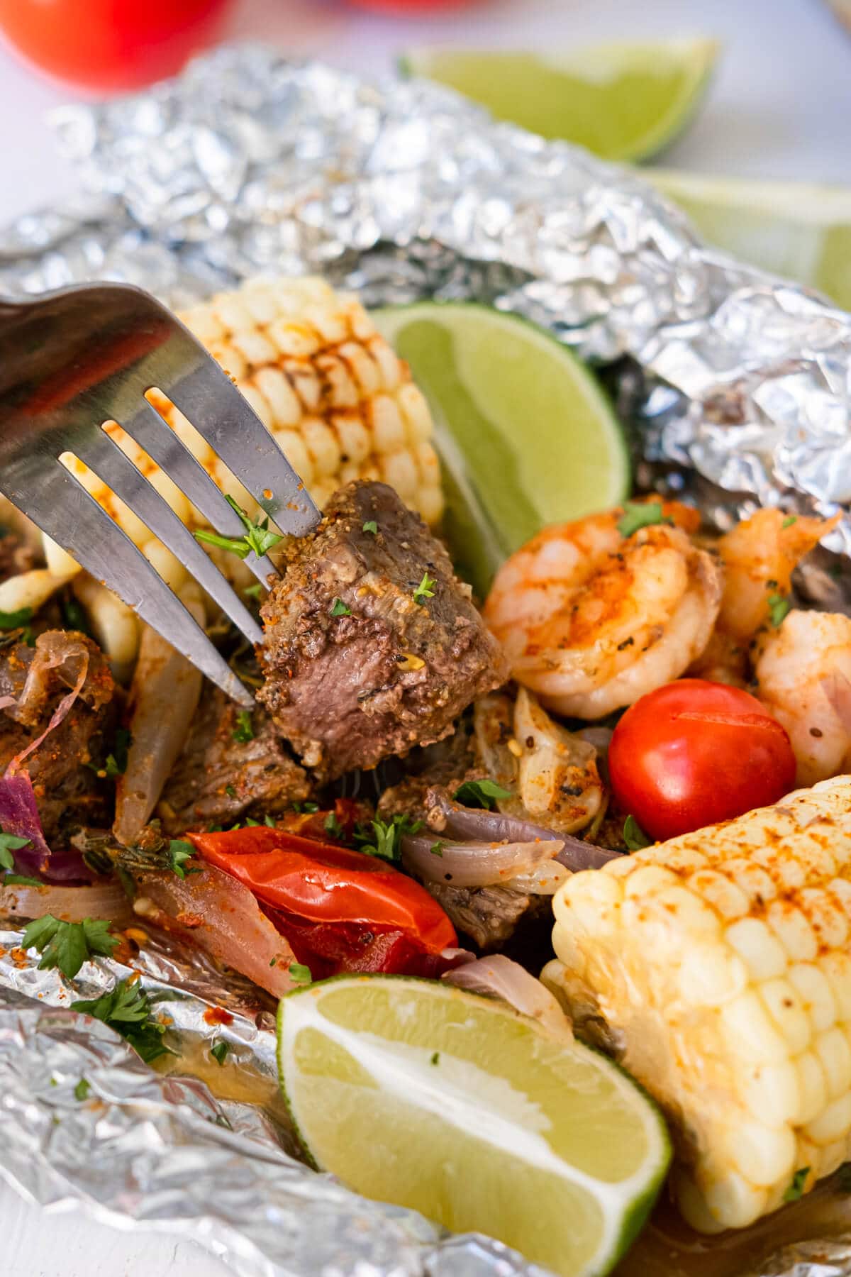 Tender, steak dice is picked by a fork over other ingredients.