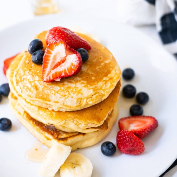 Fluffy pancakes with berries and banana on top.