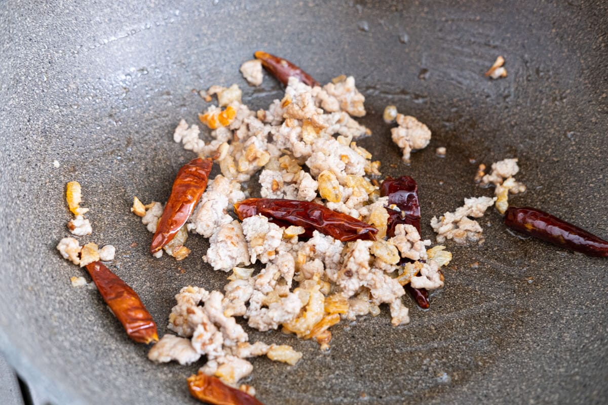 Stir-fry garlic an ginger, then add ground pork, dried shrimp and dried chili peppers in the wok. 