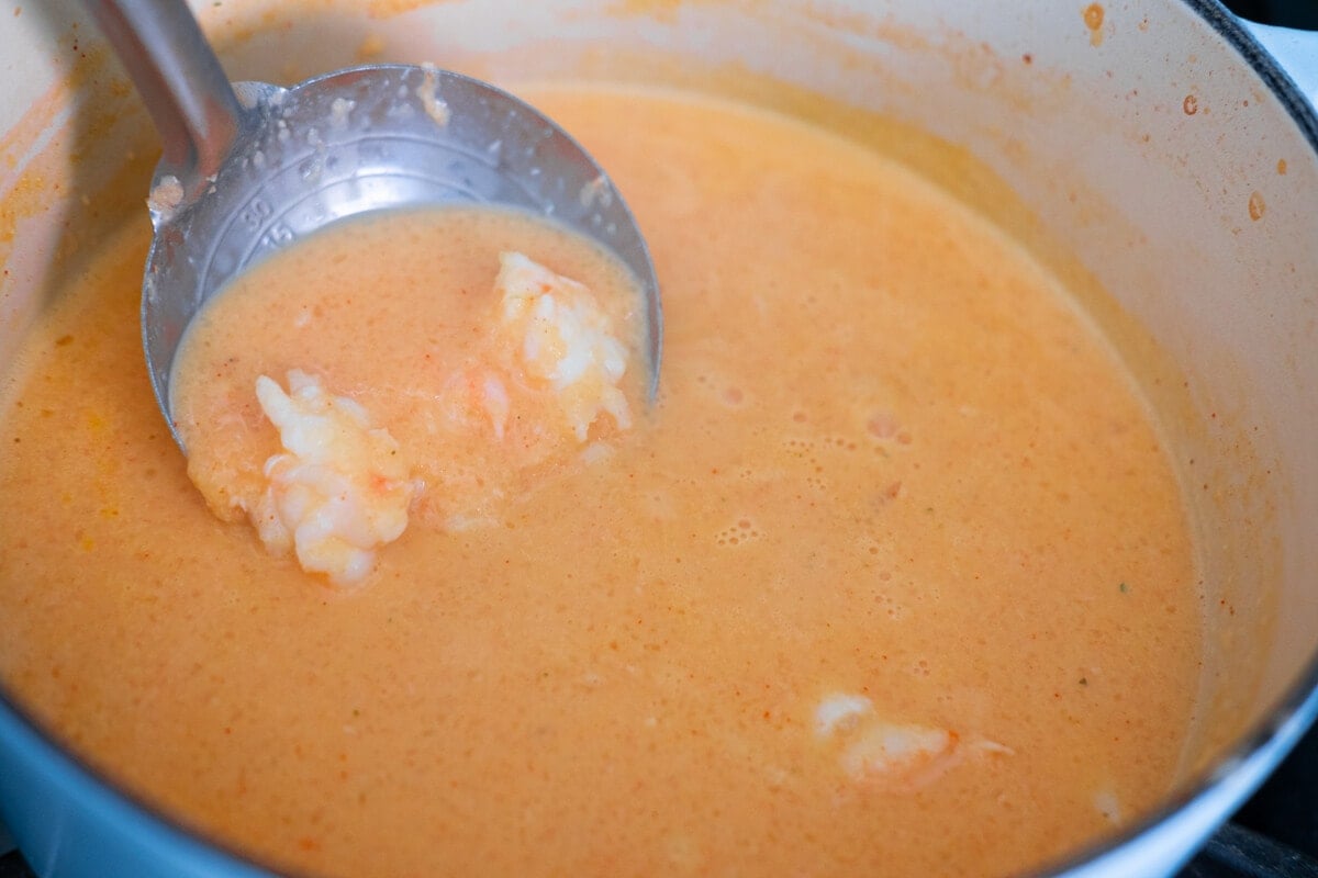 Shrimp added into the pot of soup scooped by a saddle. 