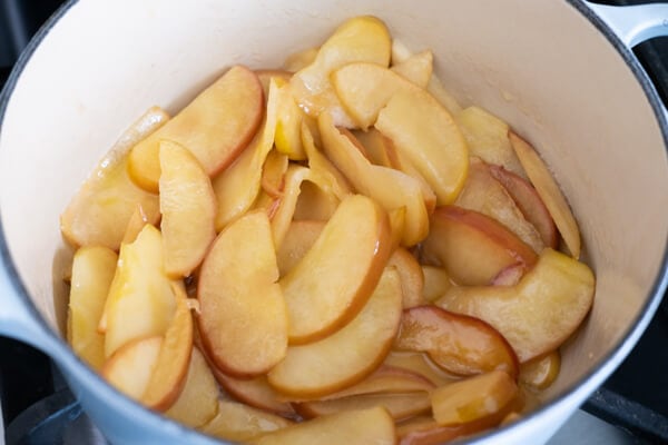 Apple slices simmering in a pot with sugar and cinnamon. 