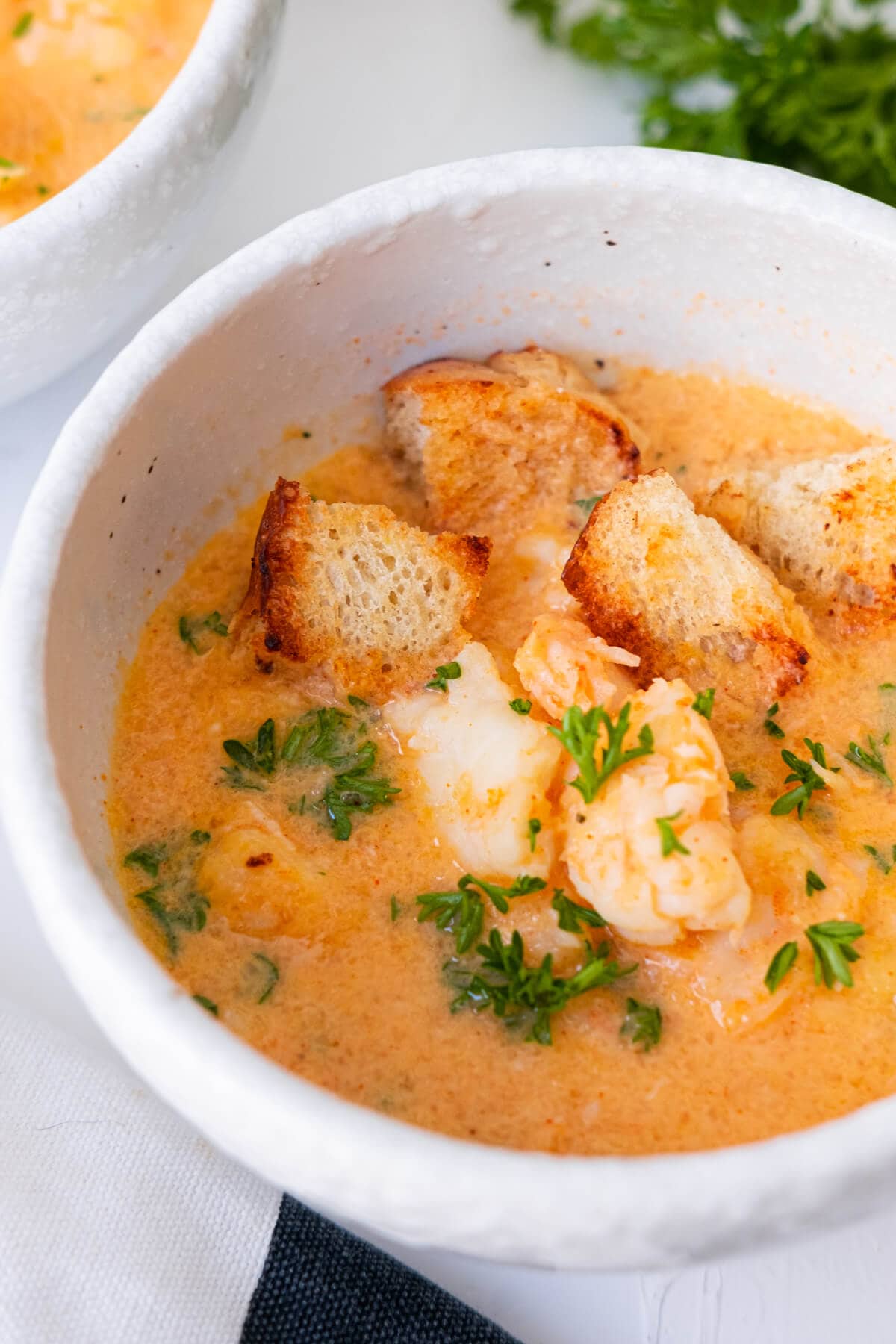 Bisque served with shrimp, crouton, and parsley on top in a bowl. 