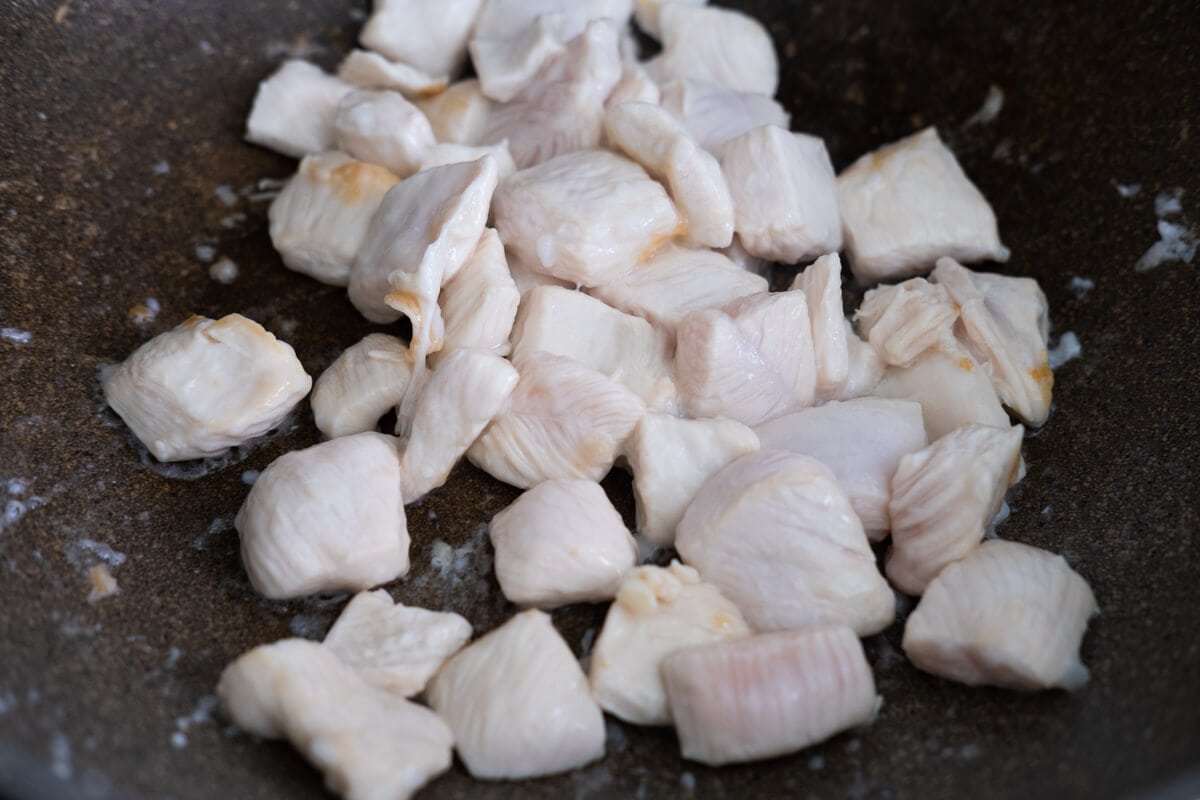 Chicken breast stir fried in a wok until opaque. 