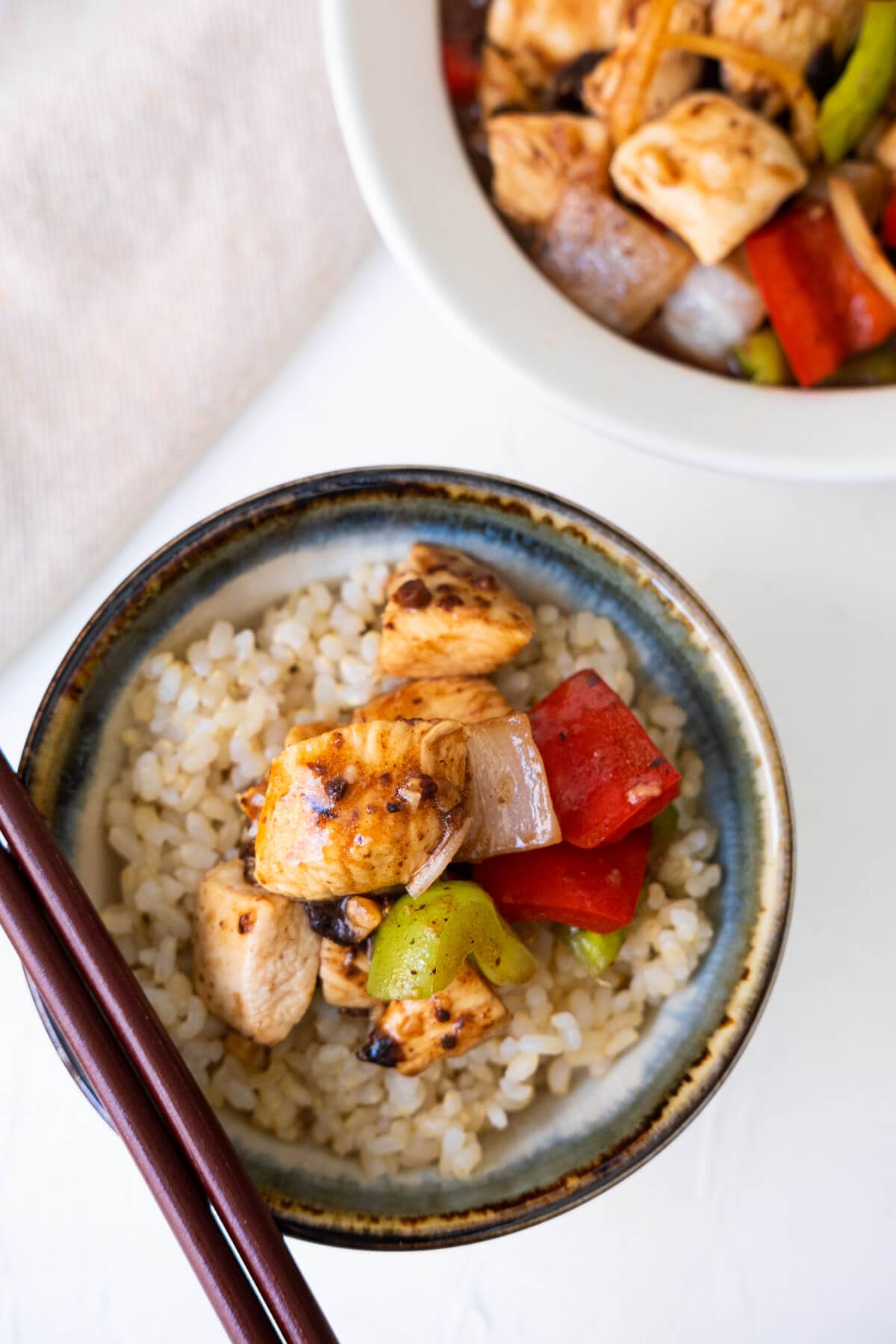 Chicken breast coated with black bean sauce with red and green bell pepper and onions served on top of a bowl of steamed rice. 