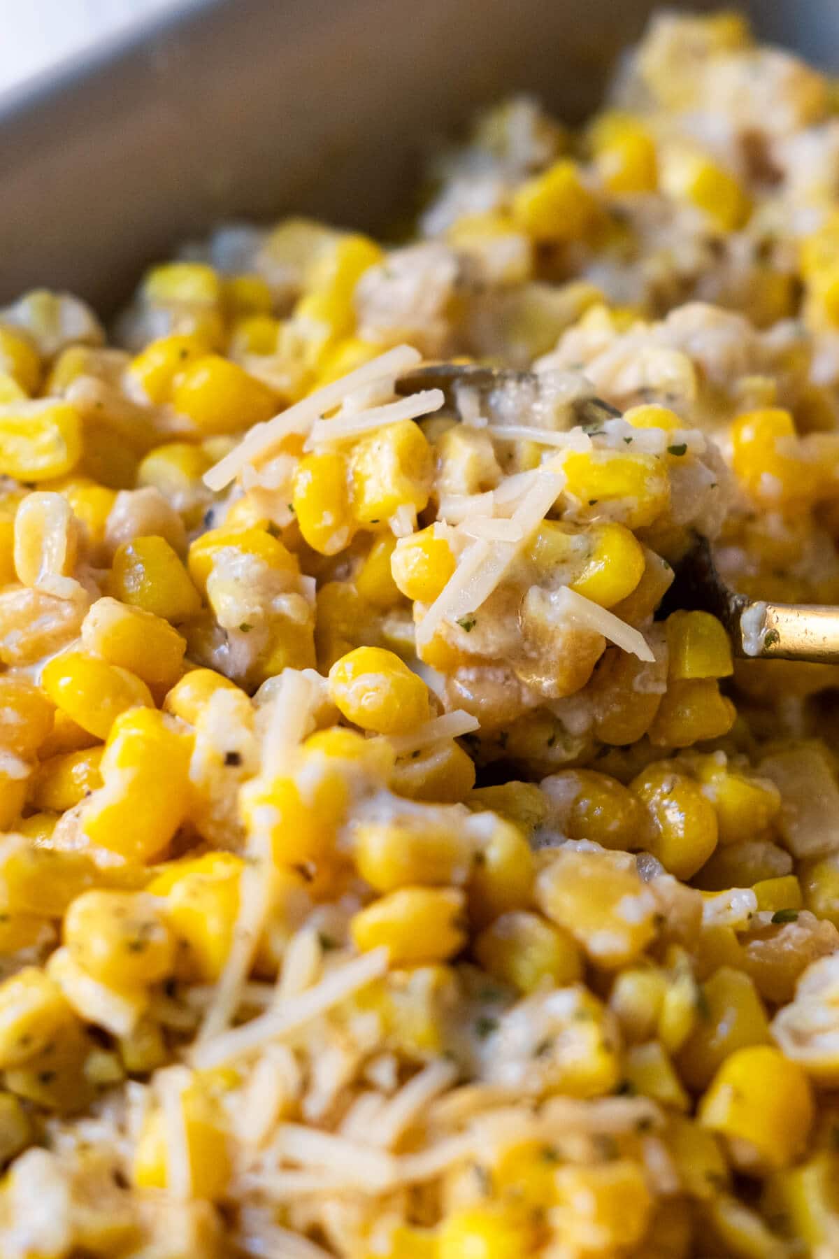 Golden sweet and cheesy baked corn scoop in a spoon. 