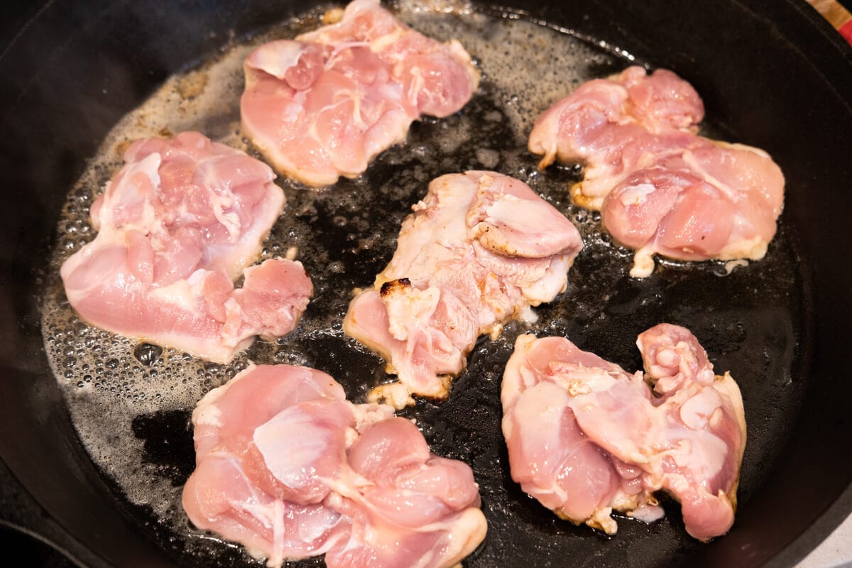 Chicken thighs seared in the skillet. 