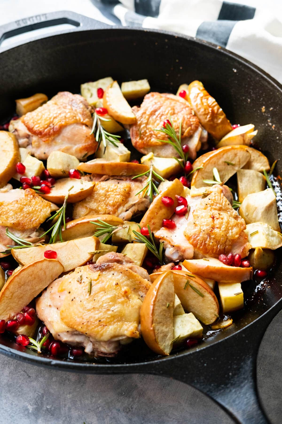 Chicken thighs glazed with apple cider roasted in a cast-iron skillet with apple, sweet potatoes and rosemary. 