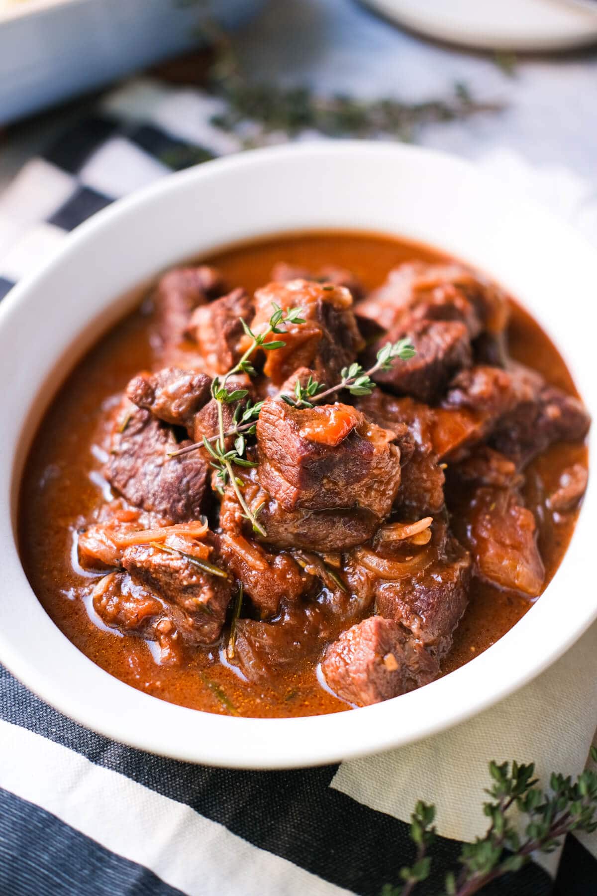 Braised beef with red wine and herbs in a white plate.