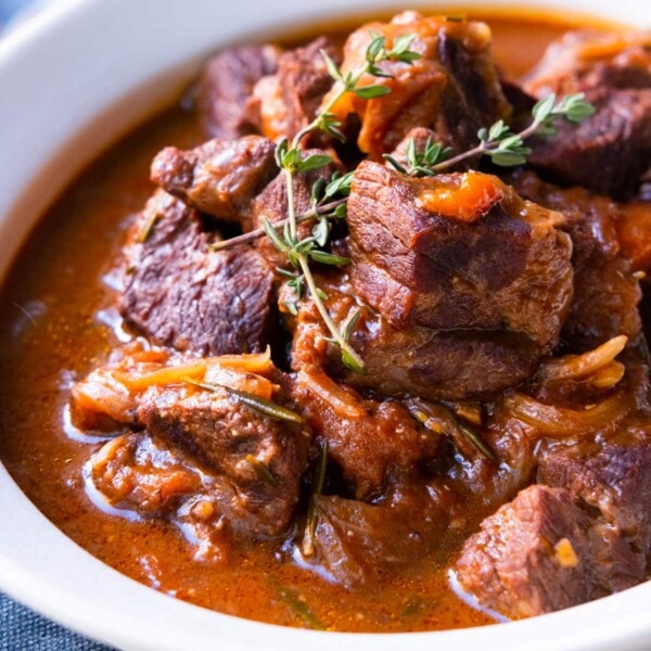 Homemade braised beef with red wine in a plate and topped with fresh thyme.