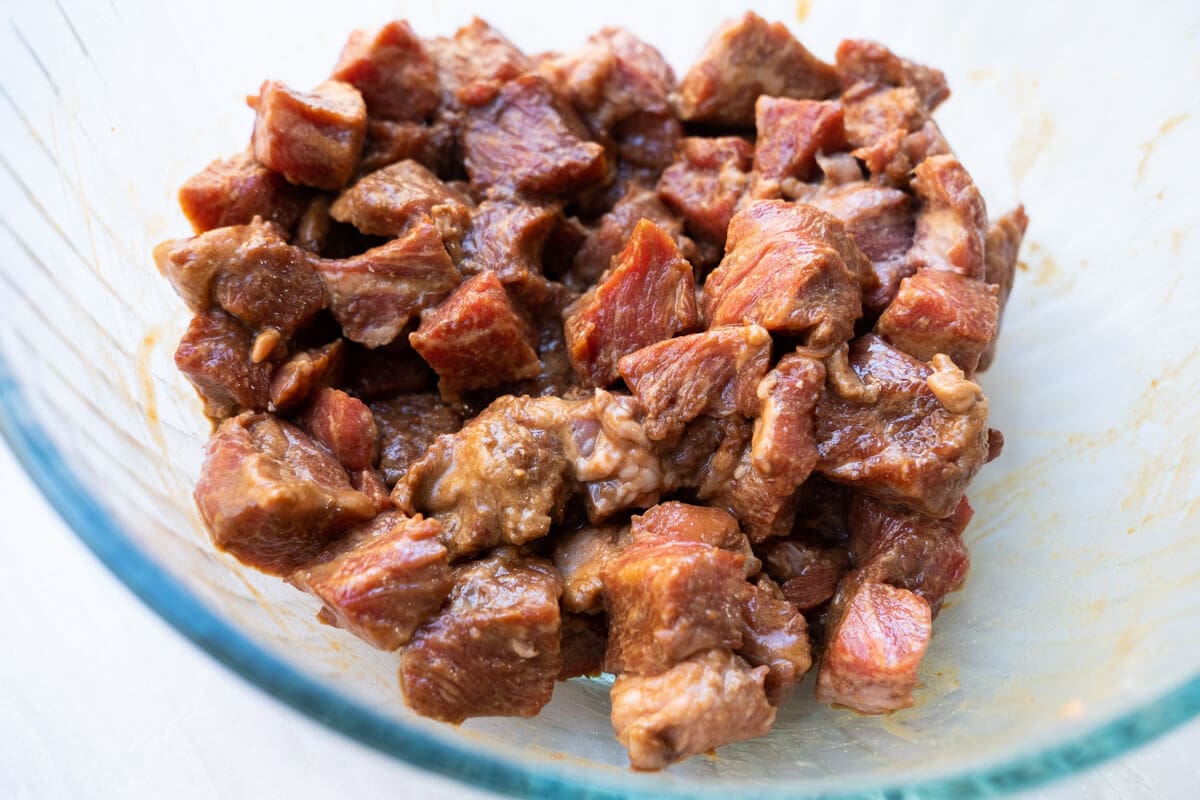 Beef manirated in soy sauce, darl soy sauce, corn starch, and baking soda in a bowl. 