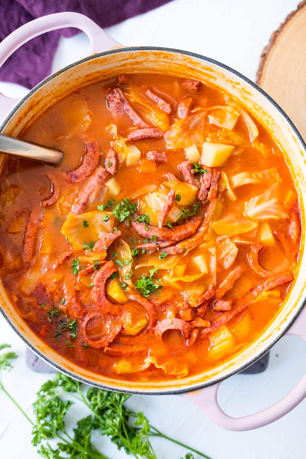 Shanghai-style borscht soup in vibrant red color and placed with fresh parsley on the side. 