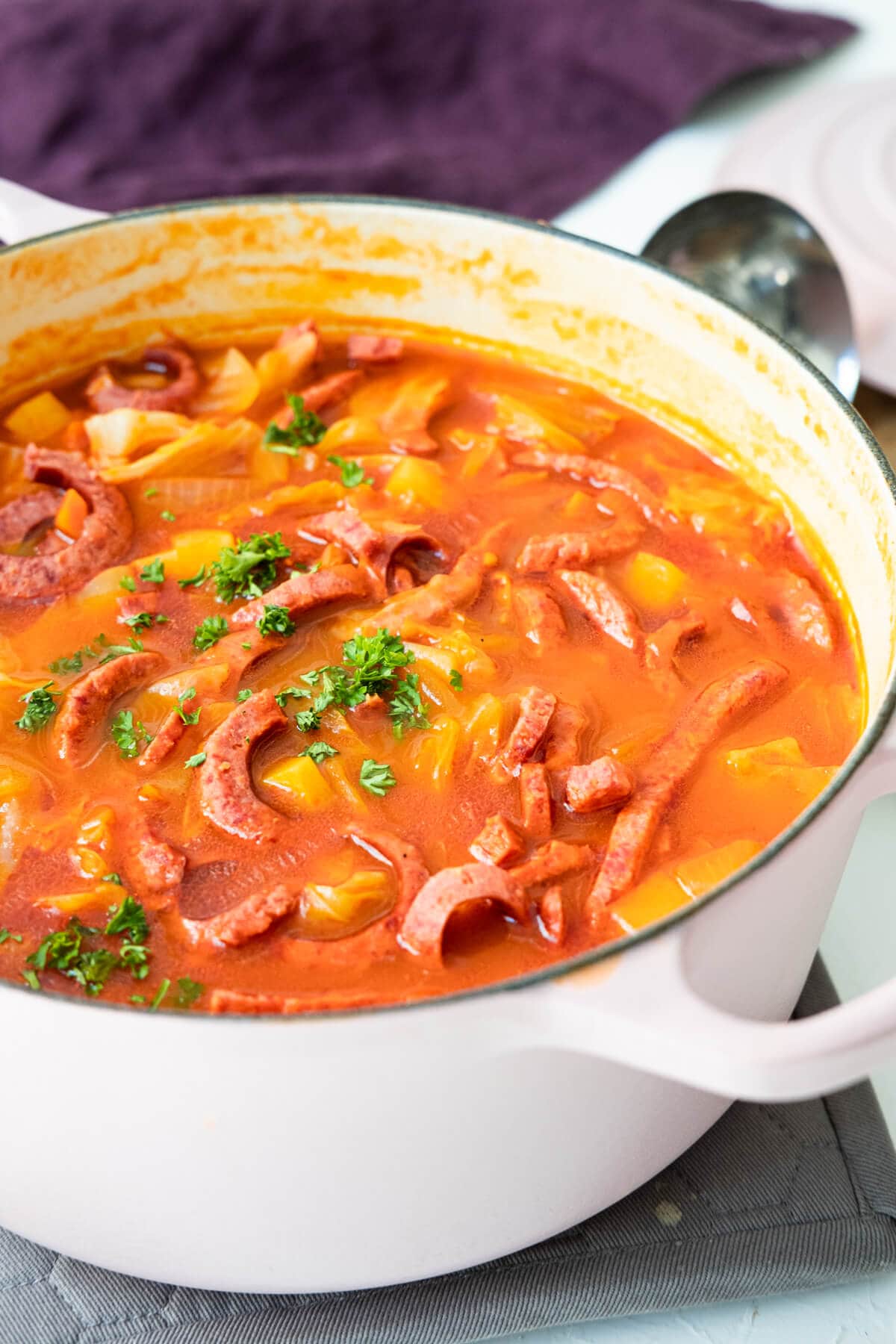 Rich and flavorful beef broth served in a pot with beef sausage, vegetables.