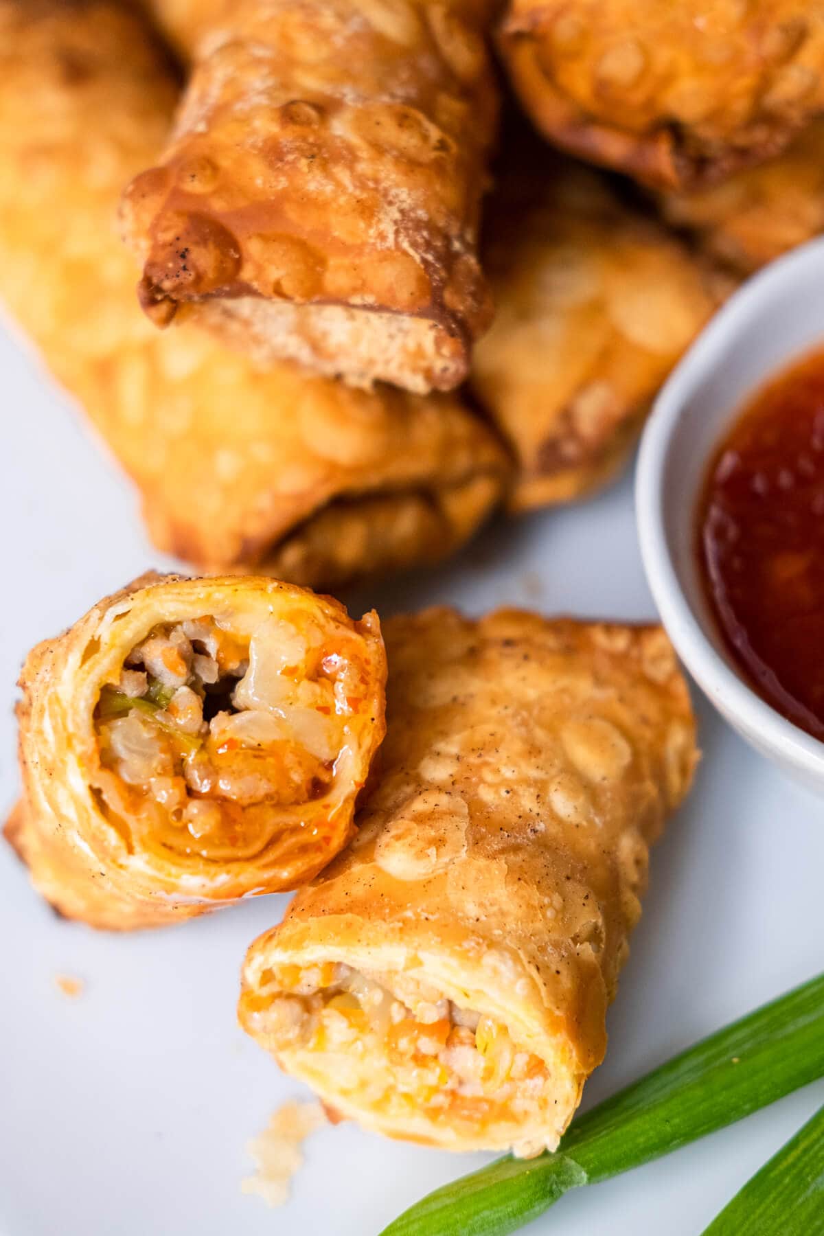 A top down shot of a half cut opened egg roll dipped with sweet chili sauce. 