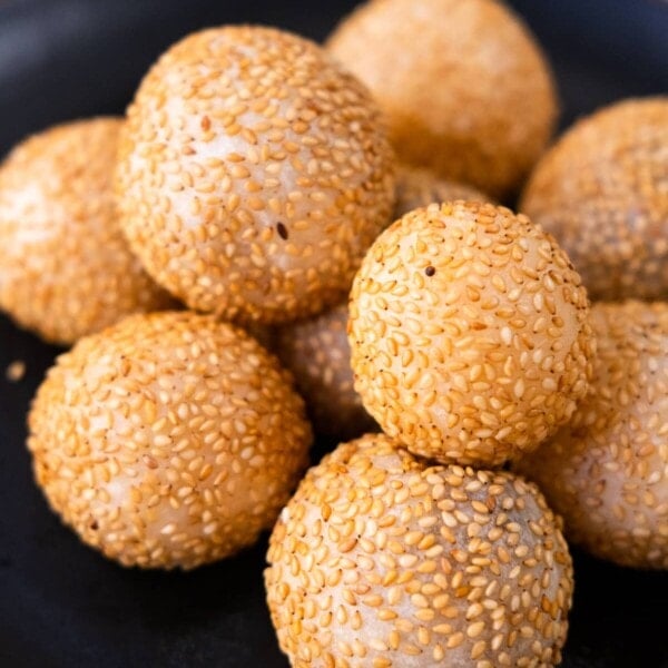 Crispy sesame balls served a black plate.