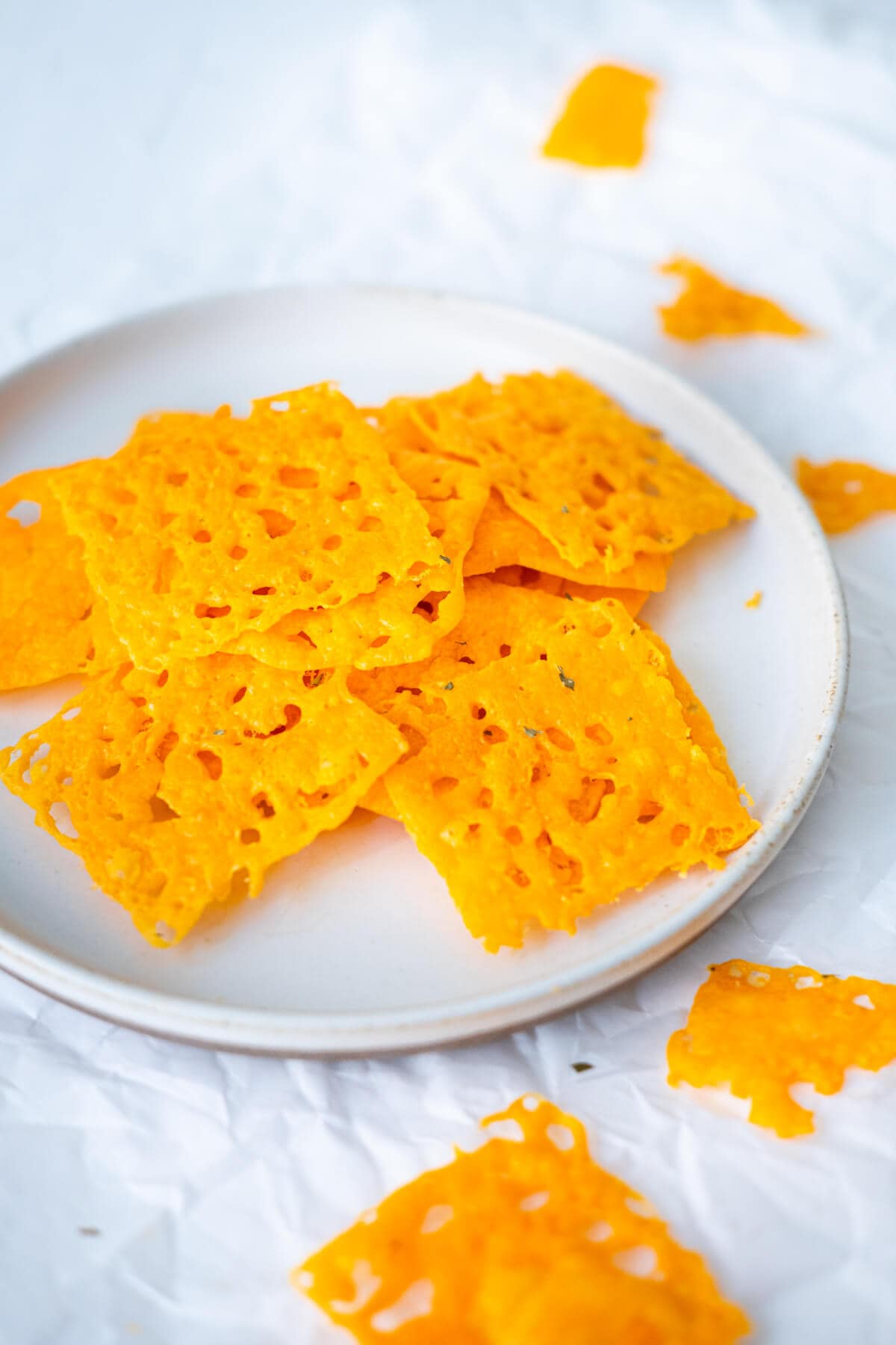 A plate of yellow crispy square crackers. 