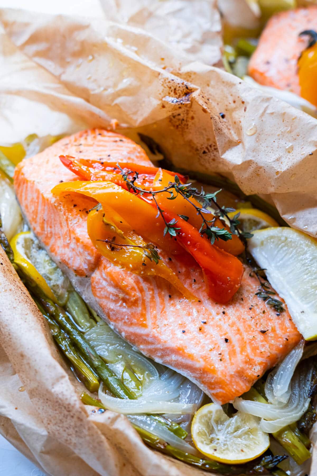 Salmon fillet coated with butter, topped with thyme and lemon zest and asparagus underneath. 