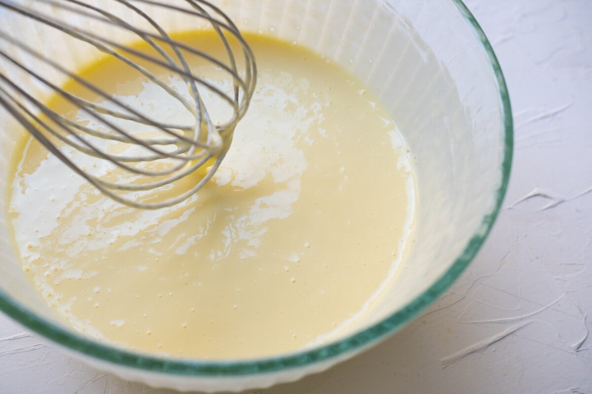 Combination of Greek yogurt, eggs, spoon, and corn starch in a bowl.