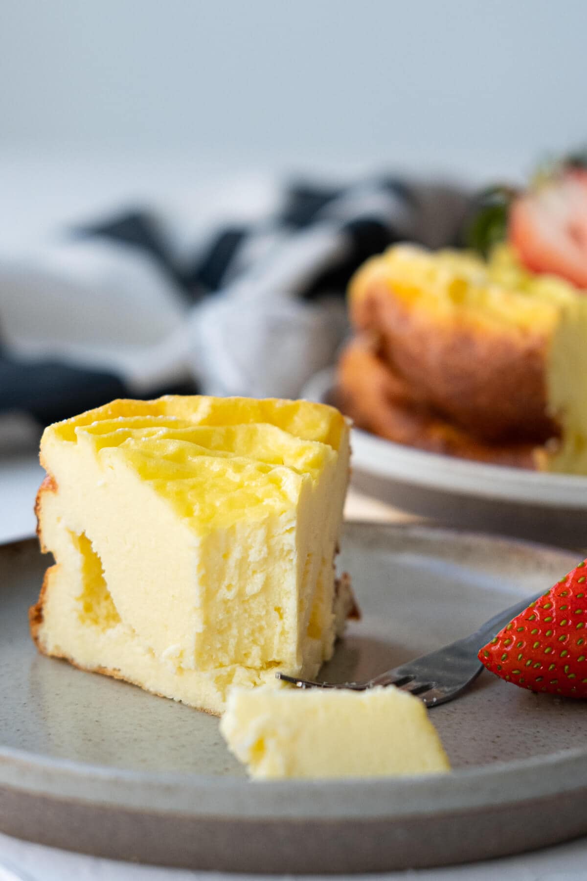 One creamy slice of greek yogurt cake with strawberry on the side.