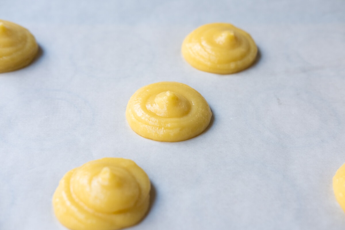 Dough mounds on a baking pan lined with parchment paper. 