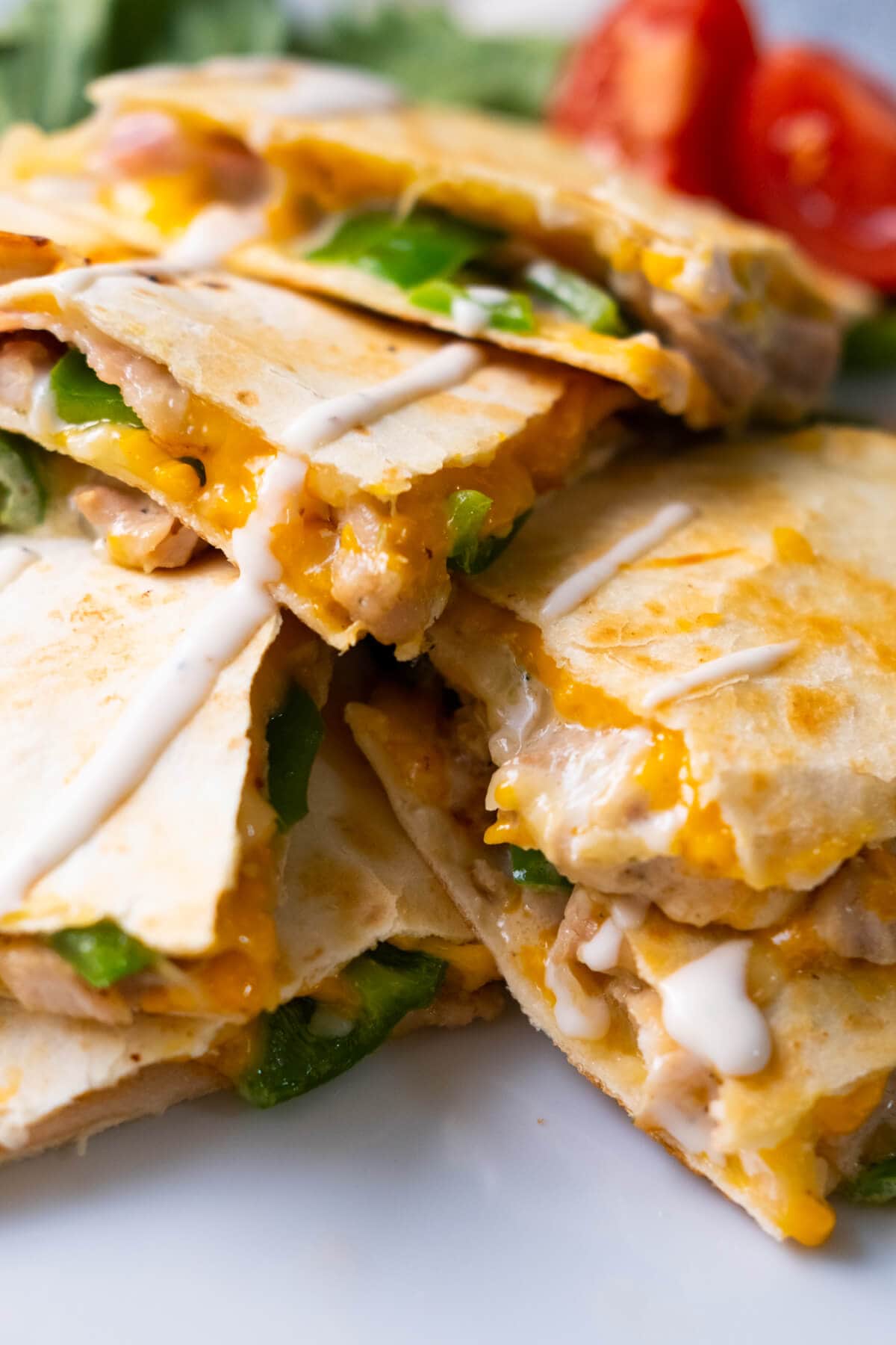 Closed up shot of cheesy chicken and bacon quesadilla with ranch drizzled on top. 