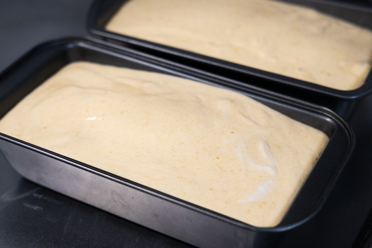 Cake batter poured over the dough in a loaf tin. 