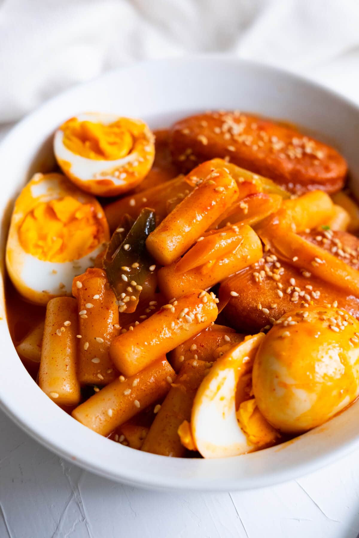 Homemade rice cake covered in a red hot sauce served with egg in a bowl. 