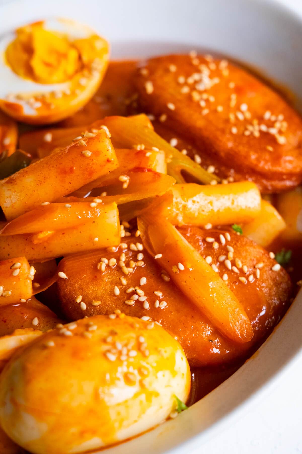 Chewy, cylindrical rice cake in spicy gochujang sauce with boiled eggs and fish cakes. 