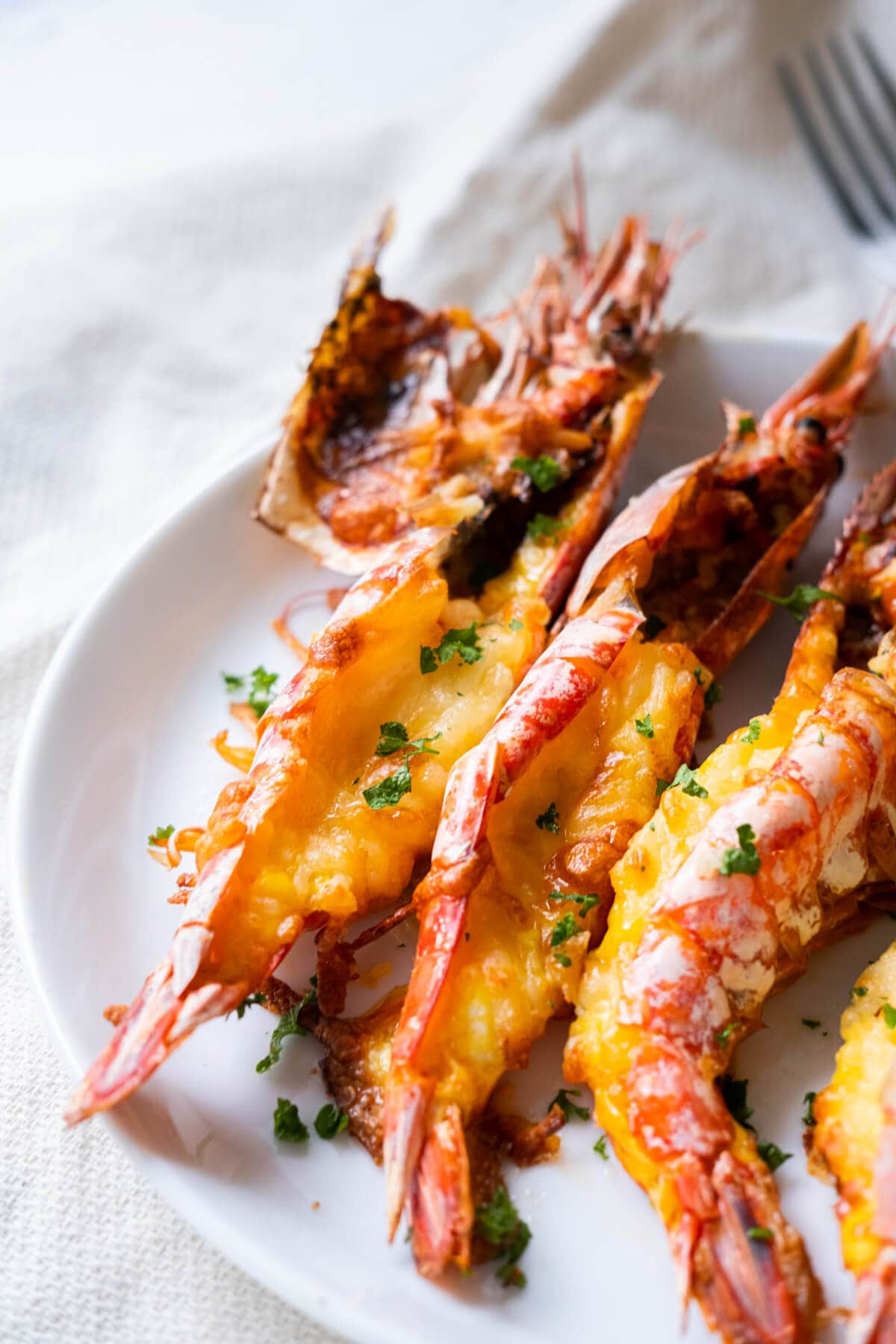 Cooked prawn with cheese melted in between served on plate. 