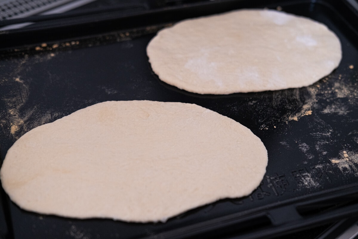 Dough flattened and rolled on placed on oven tray. 