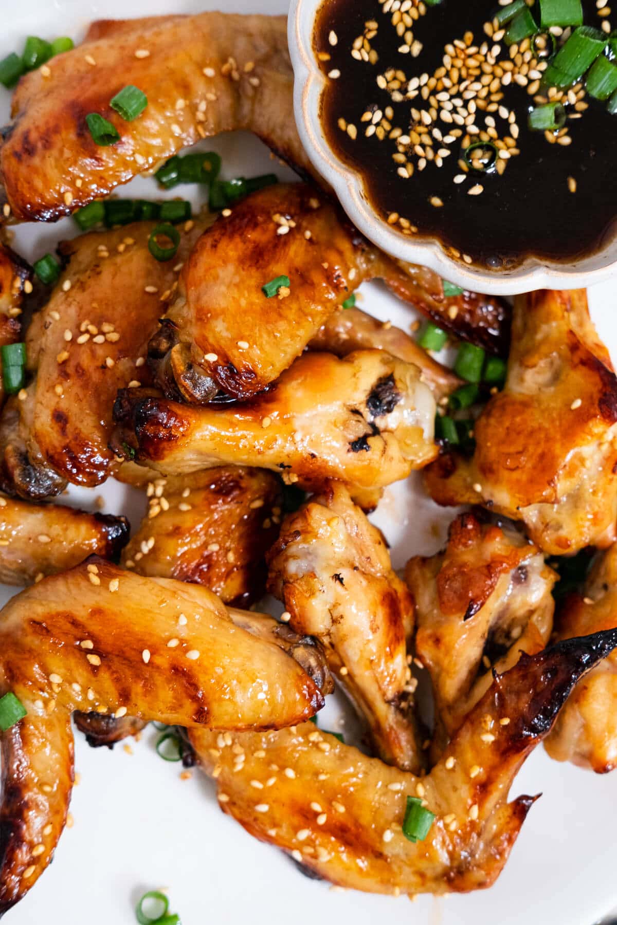 Top down photo of chicken wings served on a white plate with dipping sauce. 