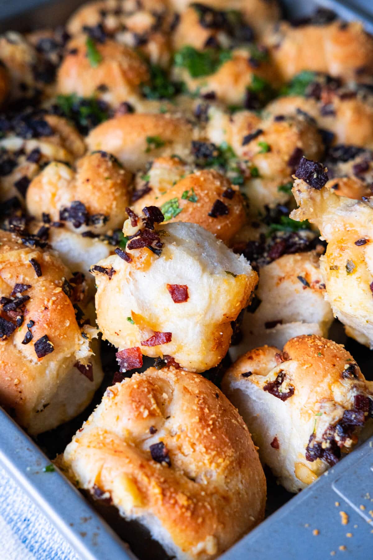 Close up shot of pepperoni garlic knots topped with freshly chopped parsley. 