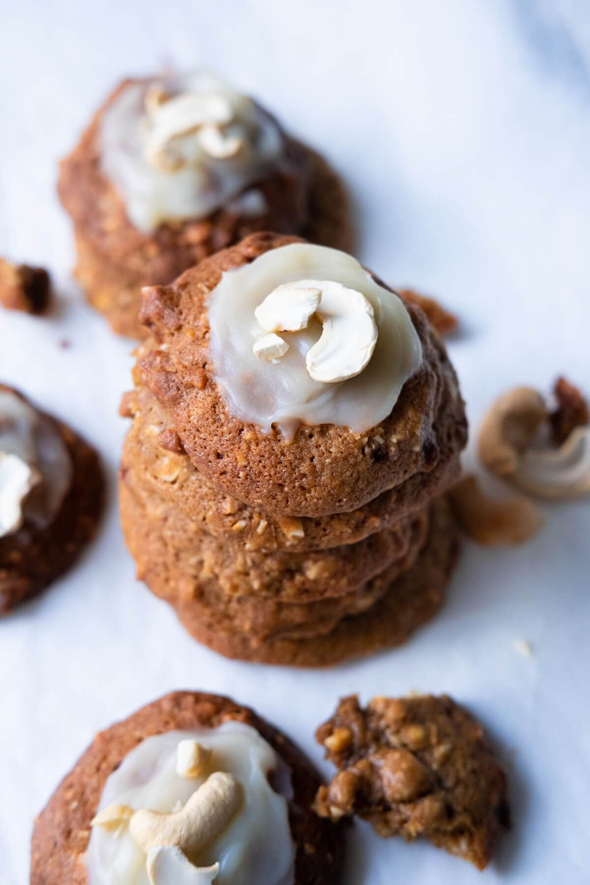 A stack of cookies with cashews and frosting on top on the table. 