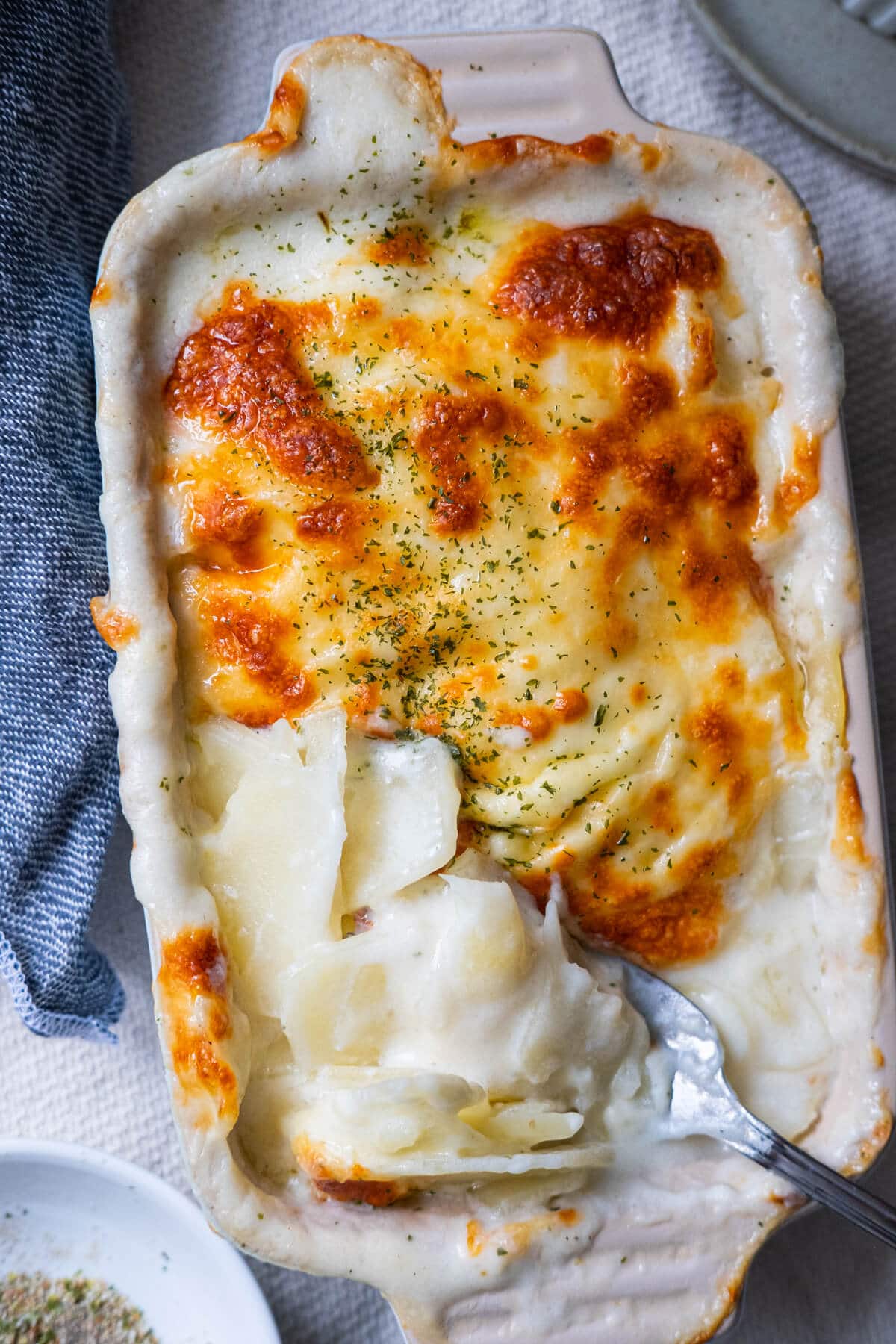 Easy potato gratin sprinkled parsley in a baking dish. 