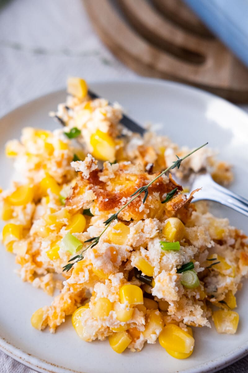 Close up shot of corn casserole served in a white shallow plate. 