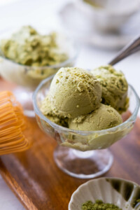 Two glass cups fill with match ice cream on a wood plate.