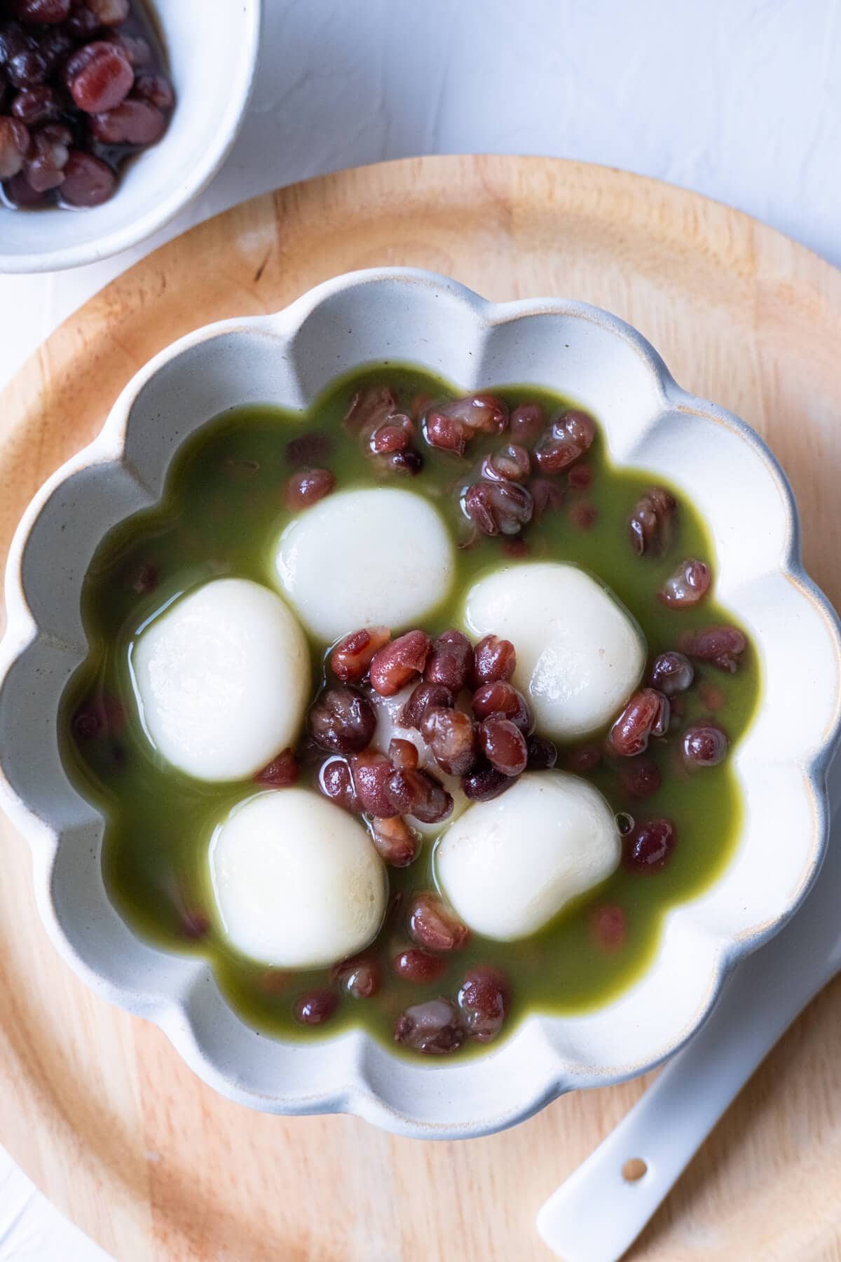 Small chewy shiratama dango lying on red bean paste and soaked in matcha tea. 