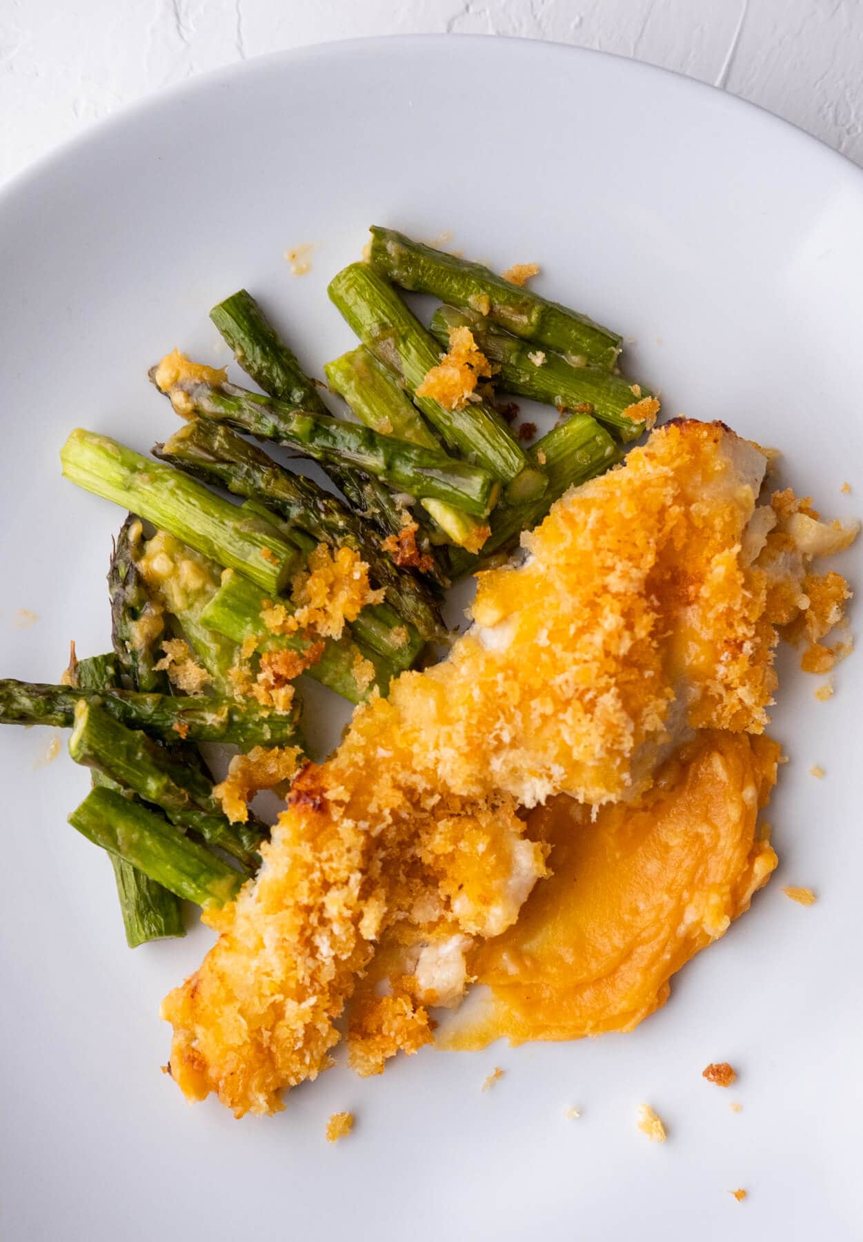 Miso butter fish with asparagus on a white shallow plate. 