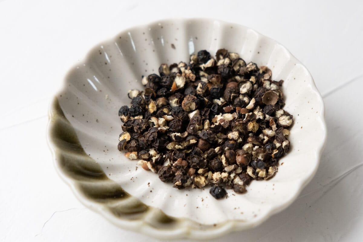 Crushed black peppercorns in a small dish. 