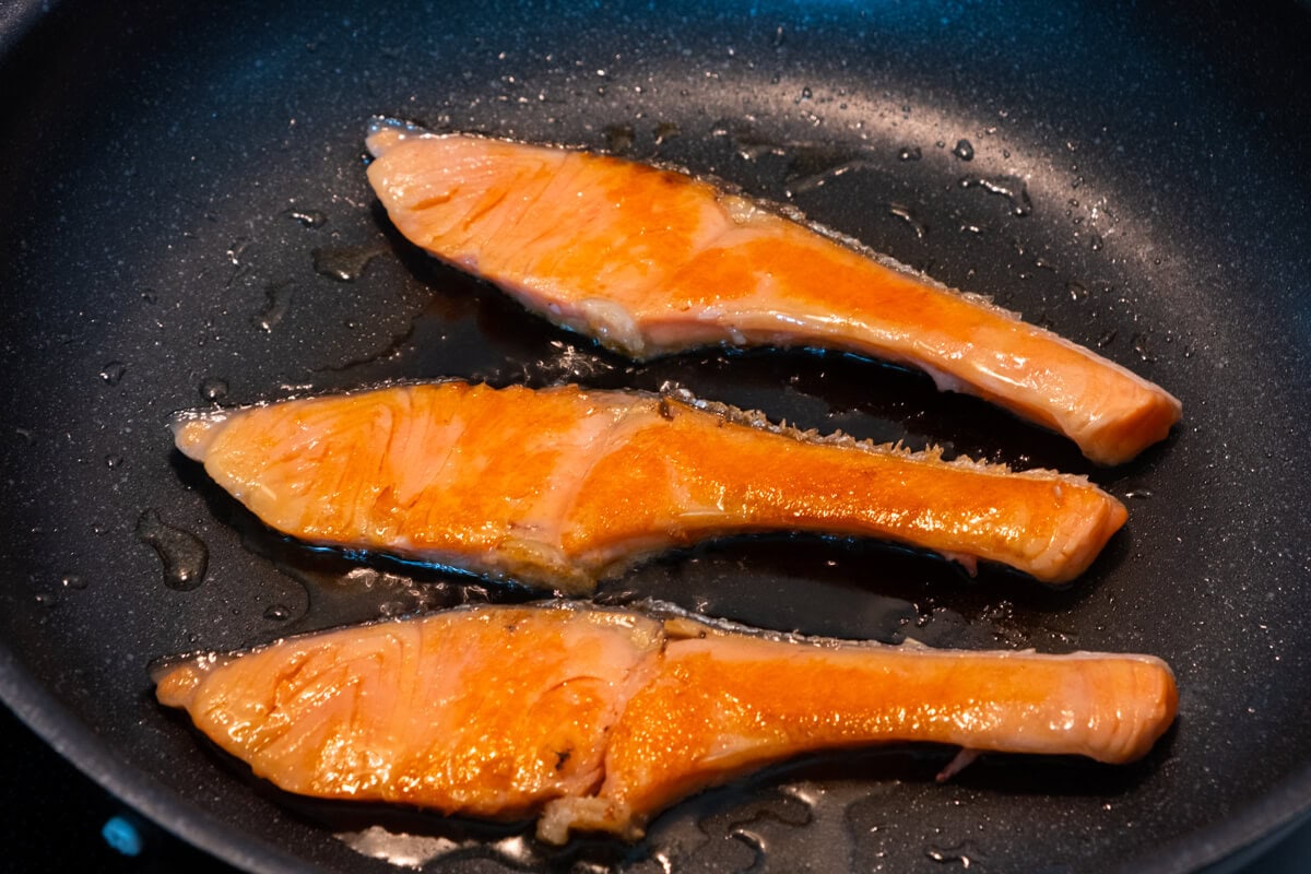 Pan searing salmon fillets on a skillet. 