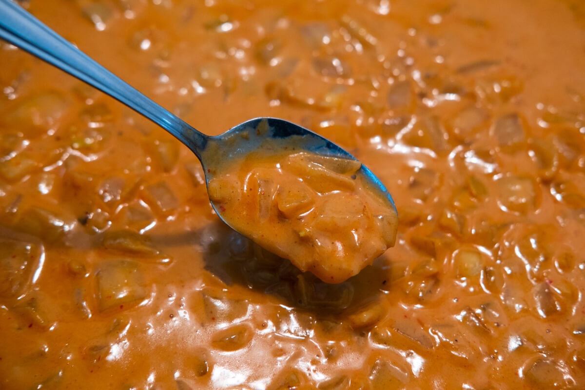 Creamy coconut chili sauce in the skillet with chopped onion. 