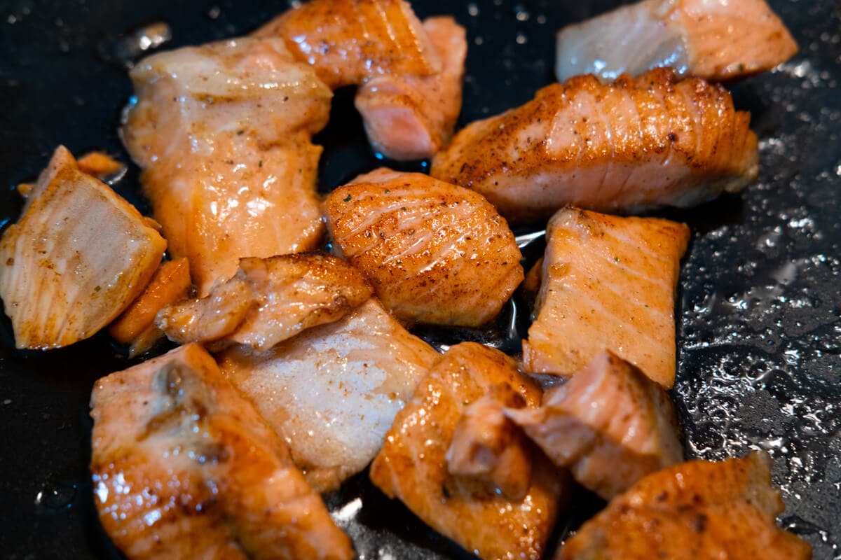 Cooking salmon cubes in a skillet. 