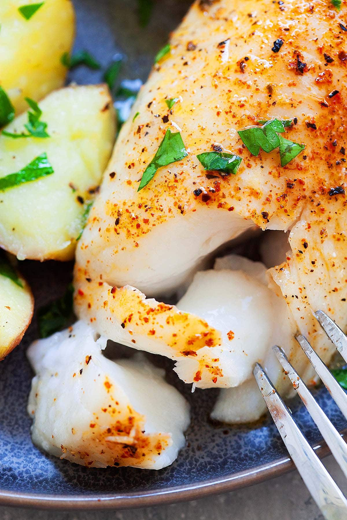 A fork piercing through a succulent baked cod fillet, unveiling its tender, flaky white flesh.