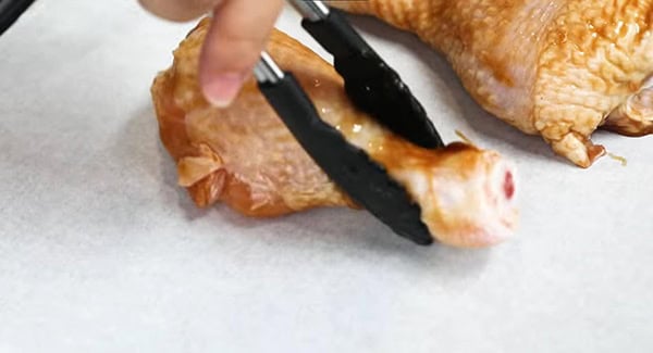 This image shows the Chicken Drumsticks being transferred over to a baking sheet.