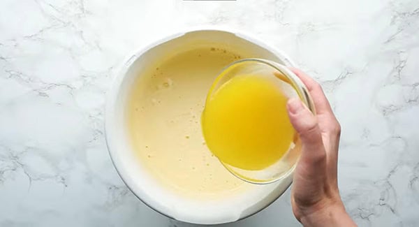 Adding melted butter in the egg and sugar mixture.