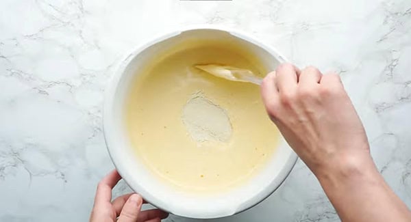 Sugar being added into the beaten egg mixture.